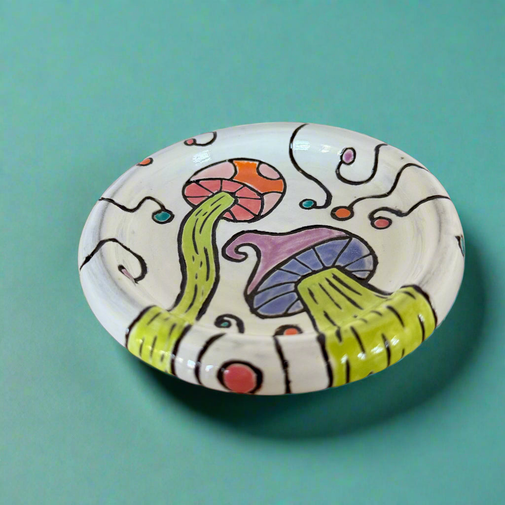 Decorative ceramic plate with colorful mushroom design on a wooden surface