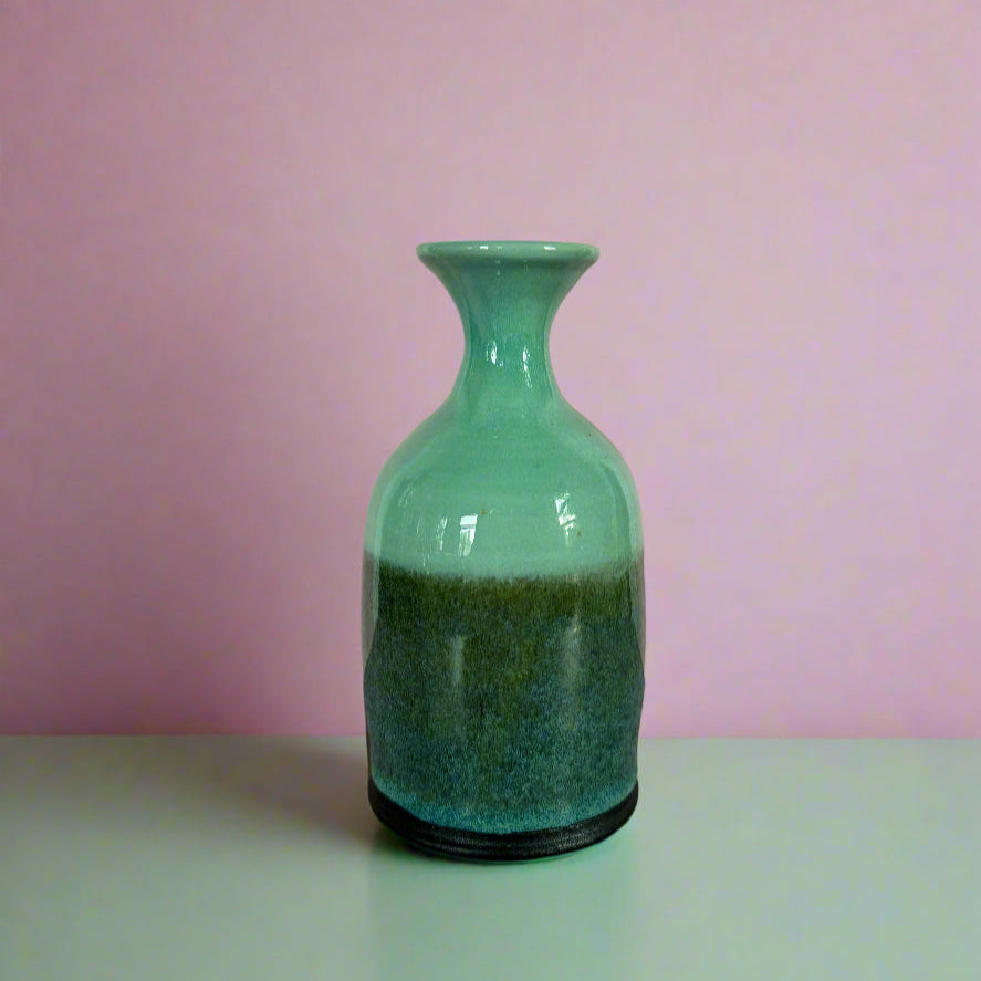 Green ceramic vase on a pink background