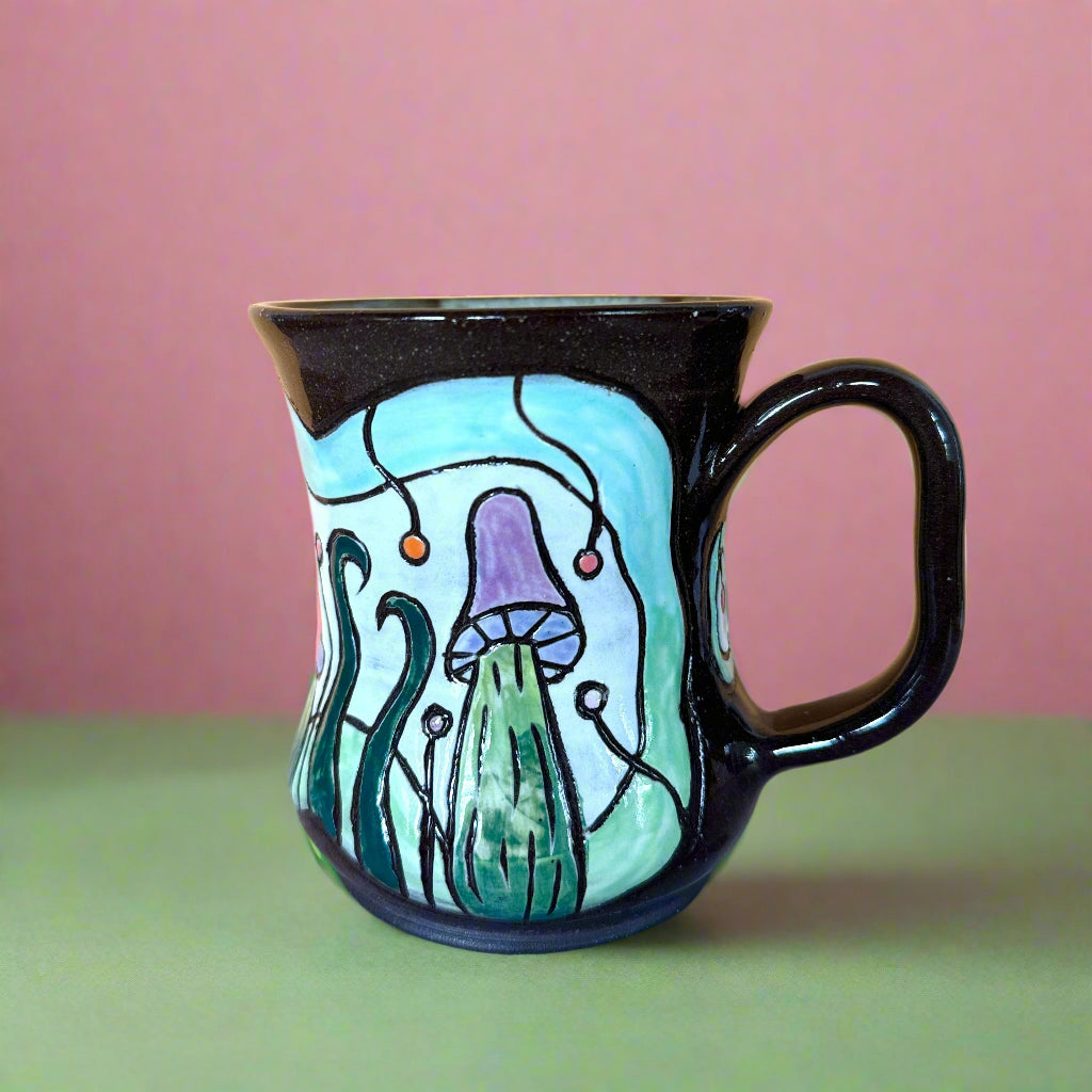 Black mug with a colorful mushroom design on a wooden surface and yellow background